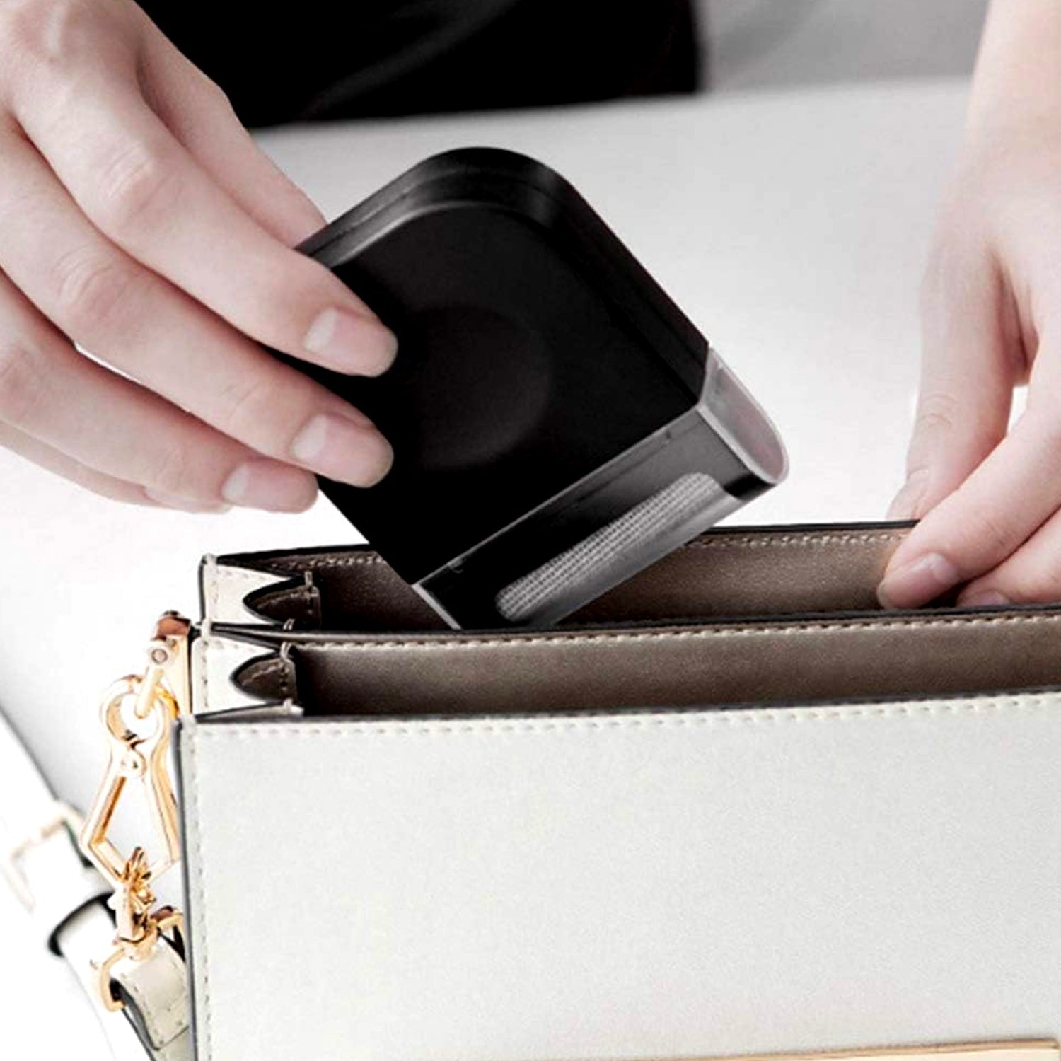 Handheld fabric shaver removing lint from a grey sweater.