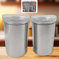 Two stainless steel airtight containers with transparent lids, filled with spices on a wooden surface.