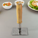 Stainless steel potato masher with wooden handle on a kitchen surface