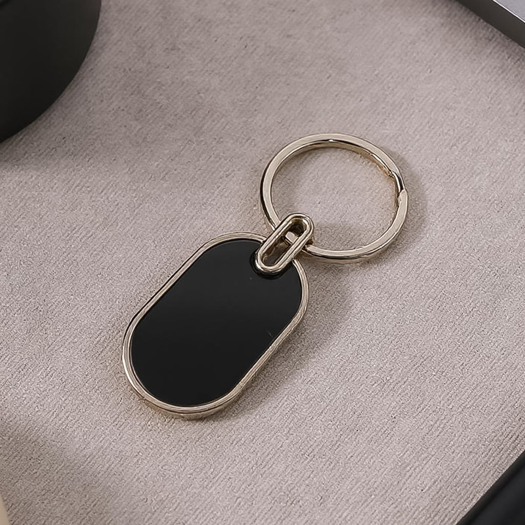 Oval metal keychain with glossy black center and polished silver frame