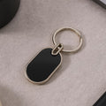Oval metal keychain with glossy black center and polished silver frame