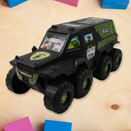 Military toy car in action on a play surface, showcasing its wheels.
