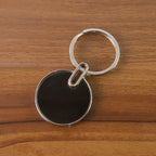 Black round metal keychain with polished chrome finish and smooth black charm
