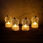 Set of four golden apple LED tealight candles glowing warmly.