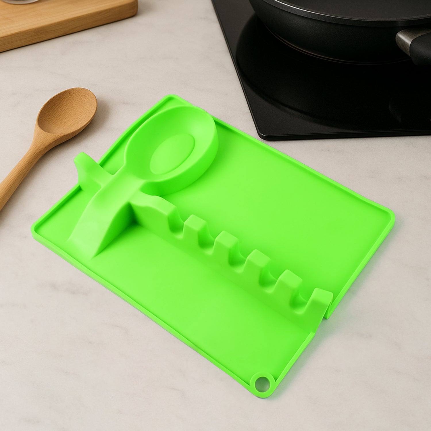 Silicone spoon rest holding a spatula, ladle, and spoon on a kitchen counter.