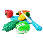 Child's hands carefully slicing a toy carrot using the plastic knife and cutting board.