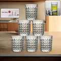 A set of six diamond-cut glass tumblers arranged neatly, showcasing their elegant design.