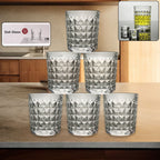 A set of six diamond-cut glass tumblers arranged neatly, showcasing their elegant design.