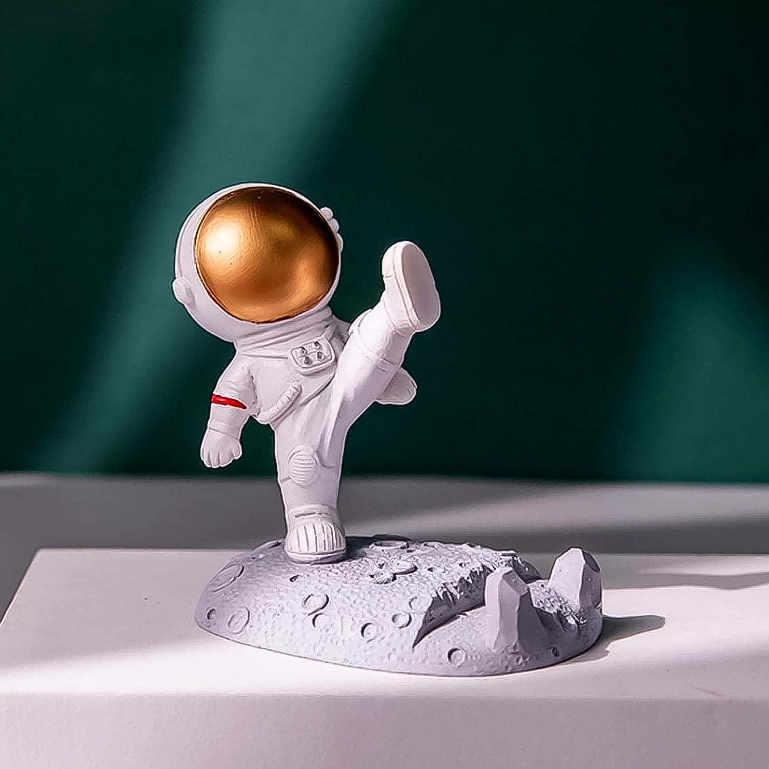 Astronaut Phone Holder (kicking leg design) on a wooden desk, holding a smartphone.