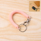 Elastic spiral coil keychain bracelet with metal key ring and clip on white background