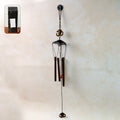 Metal wind chime with Om symbol hanging outdoors in a garden