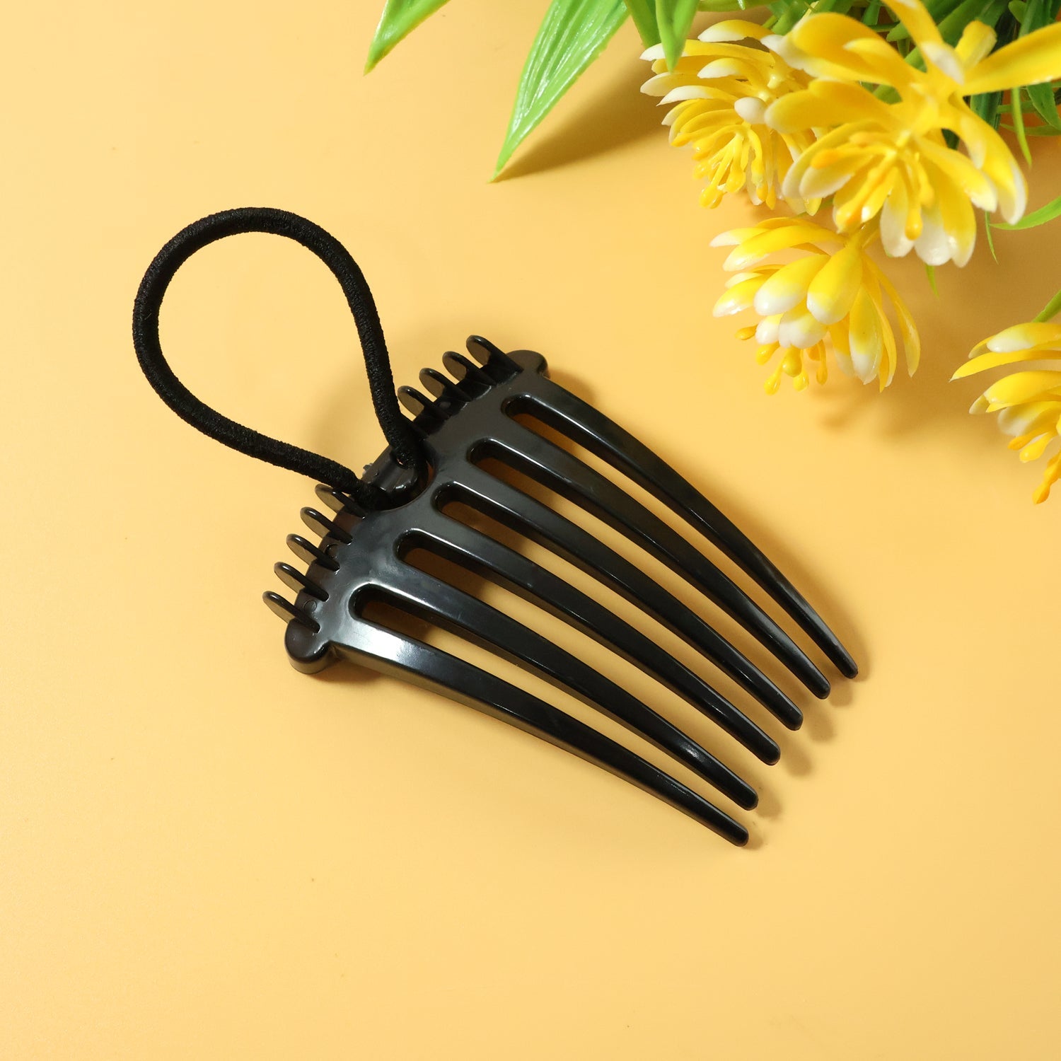 Close up of volumizing hair bun comb clip with elastic loop for secure styling