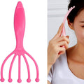 Handheld scalp massager with five metal balls resting on a warm wooden surface.