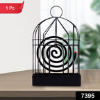 Iron birdcage mosquito coil holder placed on a rustic wooden table.
