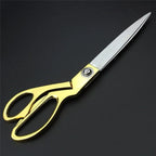 Golden tailoring scissor with sharp stainless steel blades for fabric cutting.
