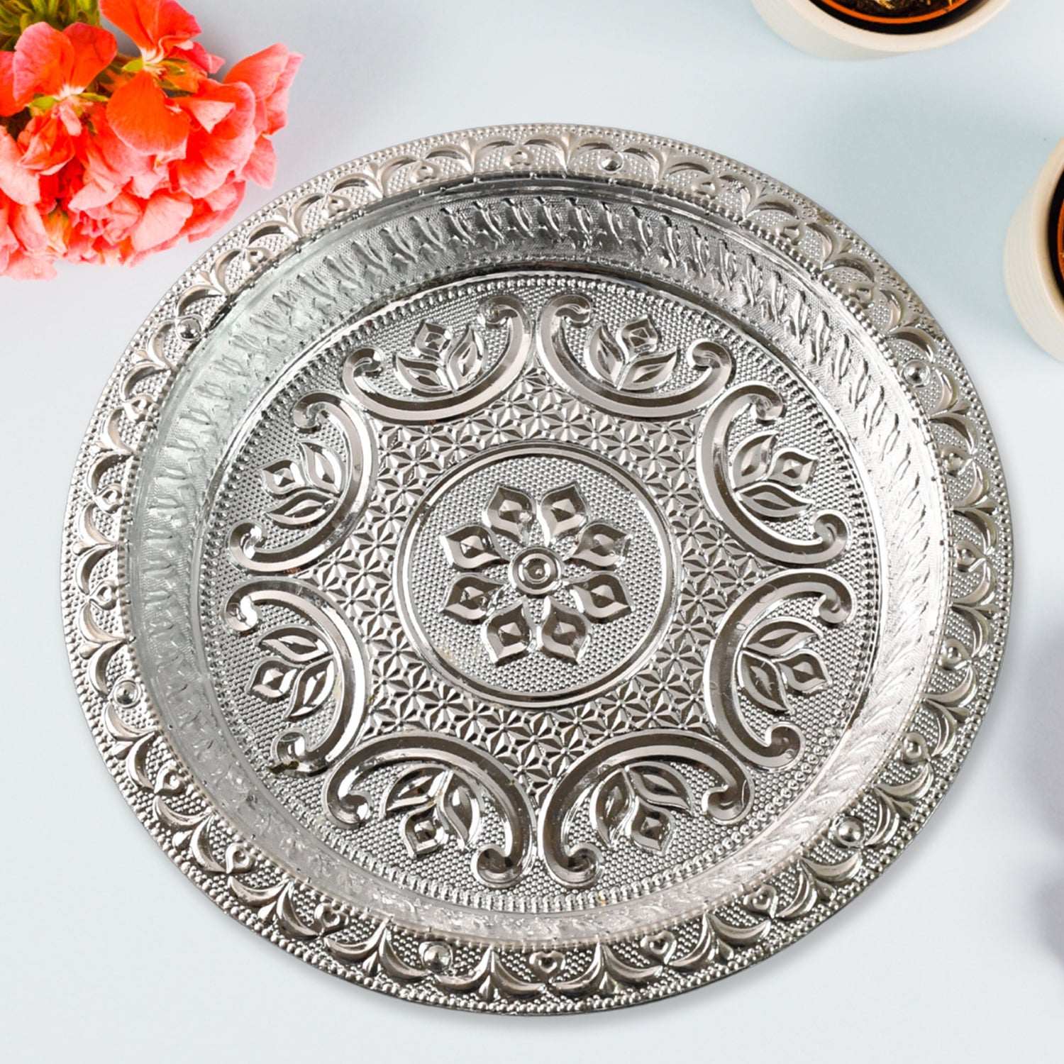 Detailed close-up of silver finish plastic pooja thali with embossed patterns