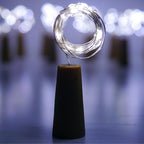 An illuminated wine bottle cork string light creating a warm ambiance on a wooden surface.