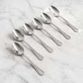 Set of 6 stainless steel dining spoons with polished finish on dining table