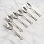 Set of 6 stainless steel dining spoons with polished finish on dining table