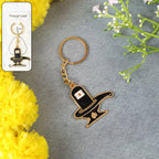 Golden Shivling keychain in metal with intricate design on plain background