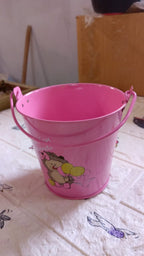 Metal planter bucket serving as a charming flower pot on a patio table.