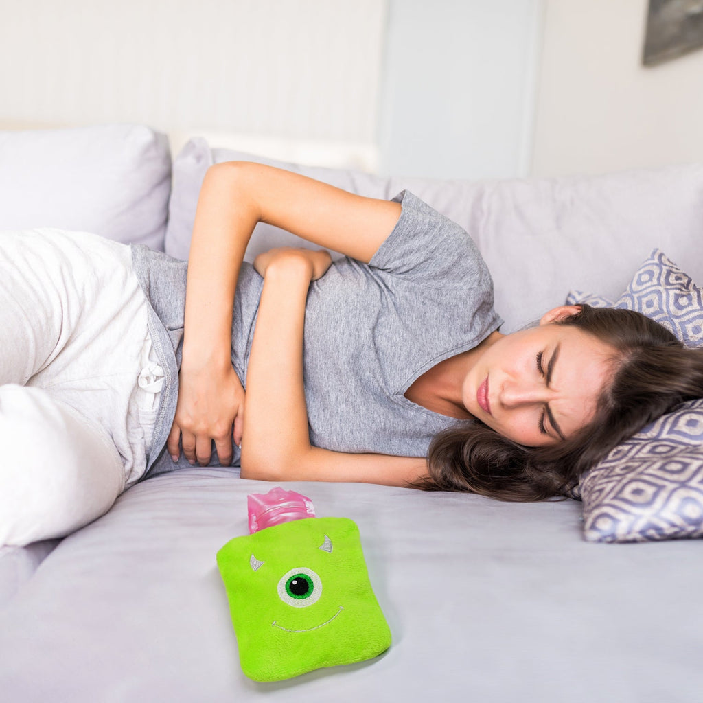 Hot water bag with monster cover placed on the abdomen for menstrual cramp relief.