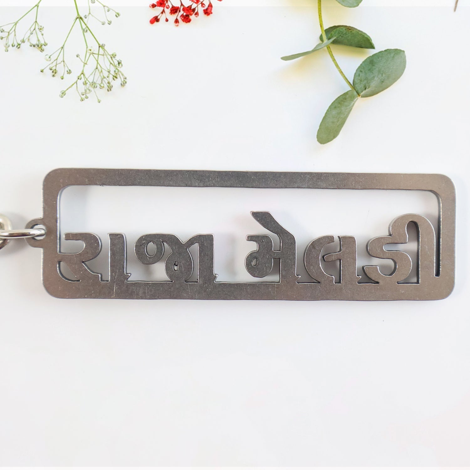 Gujarati text metal keychain featuring devotional design