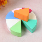A set of soft, multi-hued triangle cosmetic puffs arranged for display.