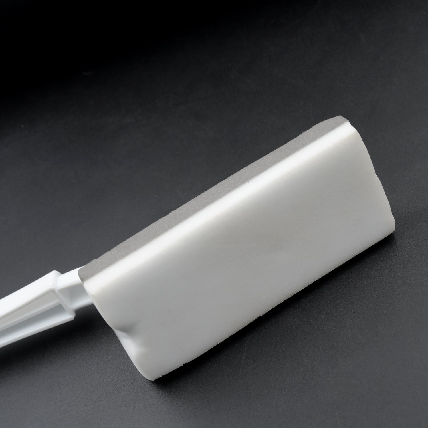 Triangle cleaning brush efficiently cleaning bathroom tiles and grout lines.