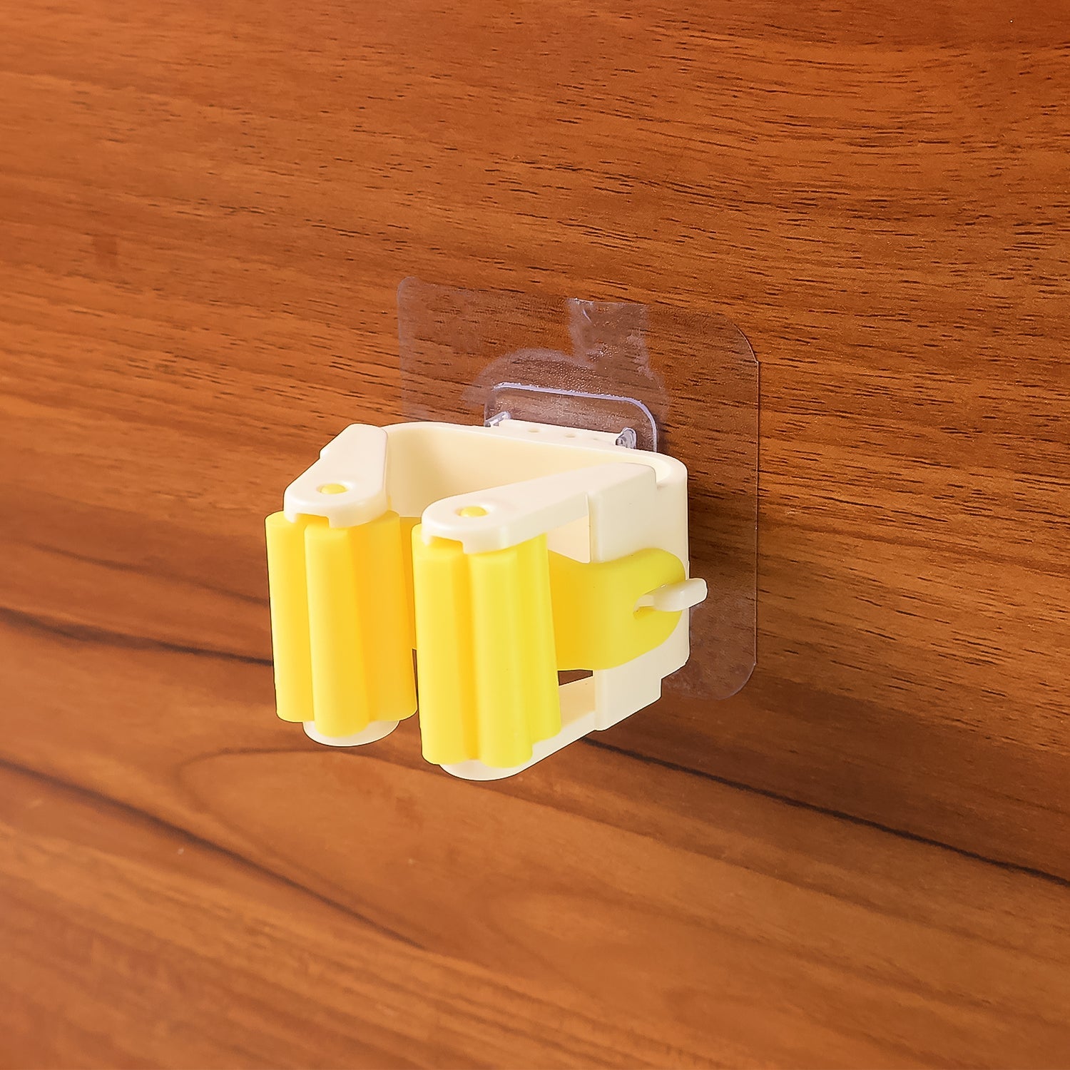 Close-up of the self-adhesive mop holder's strong spring clip gripping a broom handle.