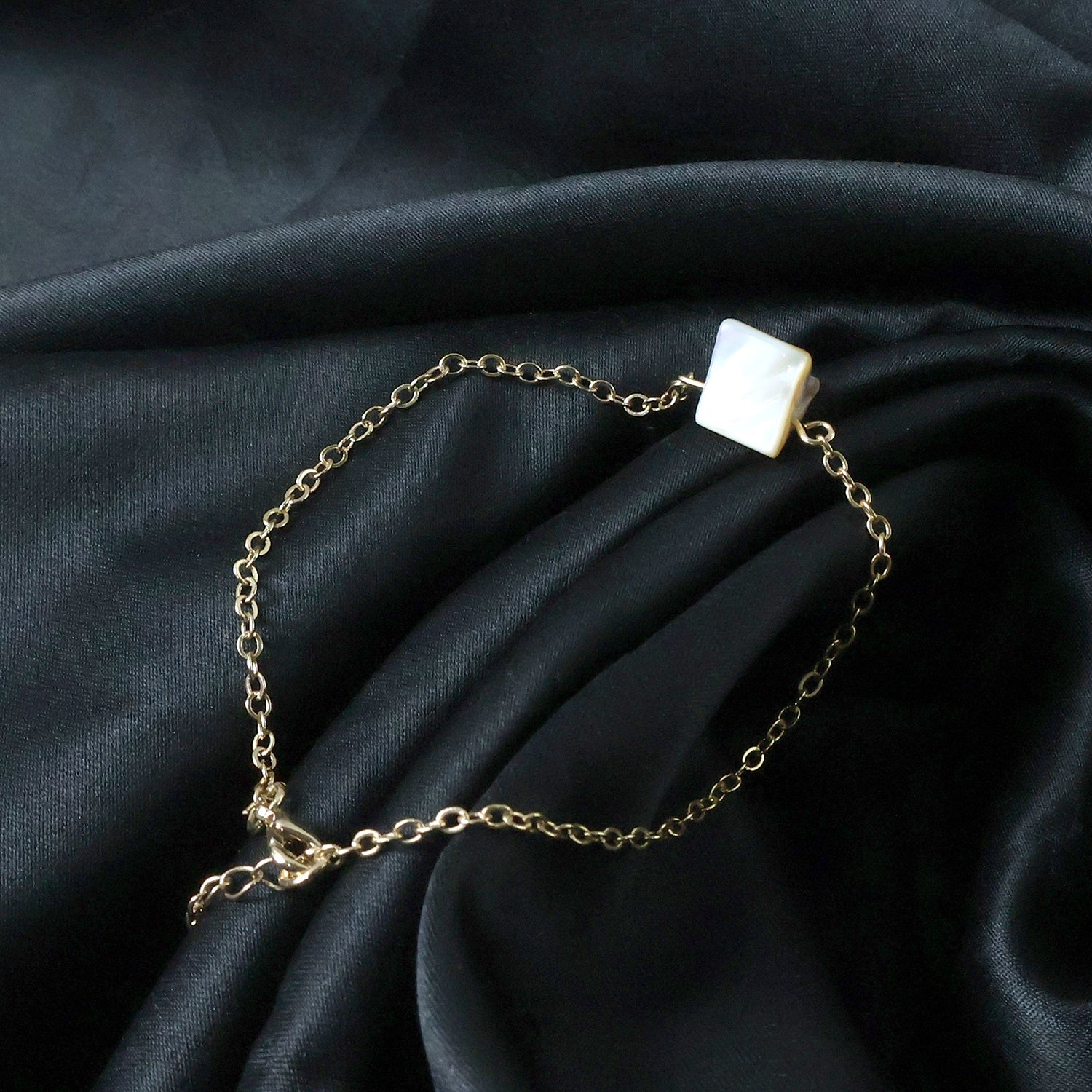Side angle of elegant chain bracelet with square stone charm