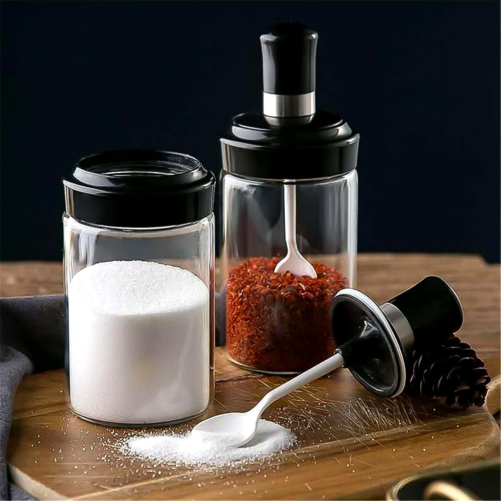 Transparent glass jar with built-in spoon for easy kitchen access to spices