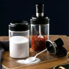 Transparent glass jar with built-in spoon for easy kitchen access to spices