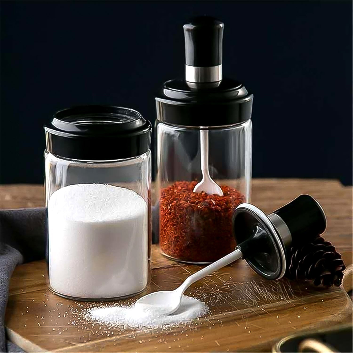 Transparent glass jar with built-in spoon for easy kitchen access to spices