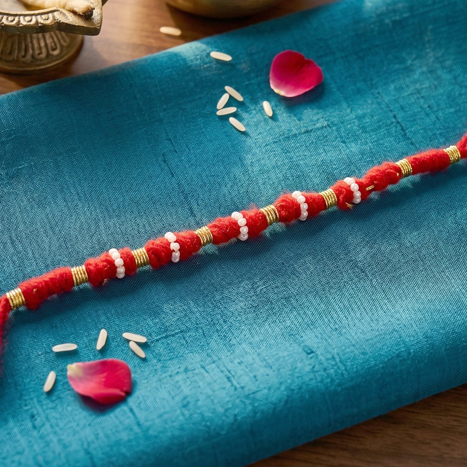 Traditional red rakhi featuring pearl and golden bead work