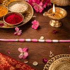 Close-up of Pink & White Thread Rakhi with golden beads