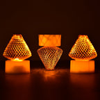A close-up view of multiple Flameless LED Tea Light Candles glowing warmly on a dark surface.
