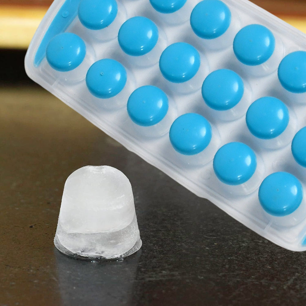 A hand gently pushing out round mini ice cubes from the flexible silicone tray.