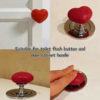 Shiny red heart-shaped knob reflecting light on a clean surface.