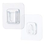 Single clear adhesive hook securely mounted on a smooth wall surface.
