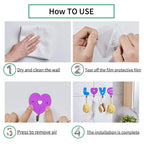 Set of three love shape self adhesive hooks on a clean white wall.