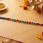 Traditional red rakhi with pearl and gold bead decorations