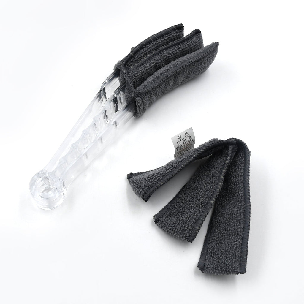 The compact blind cleaner brush being used to clean dust from a car's AC vent.