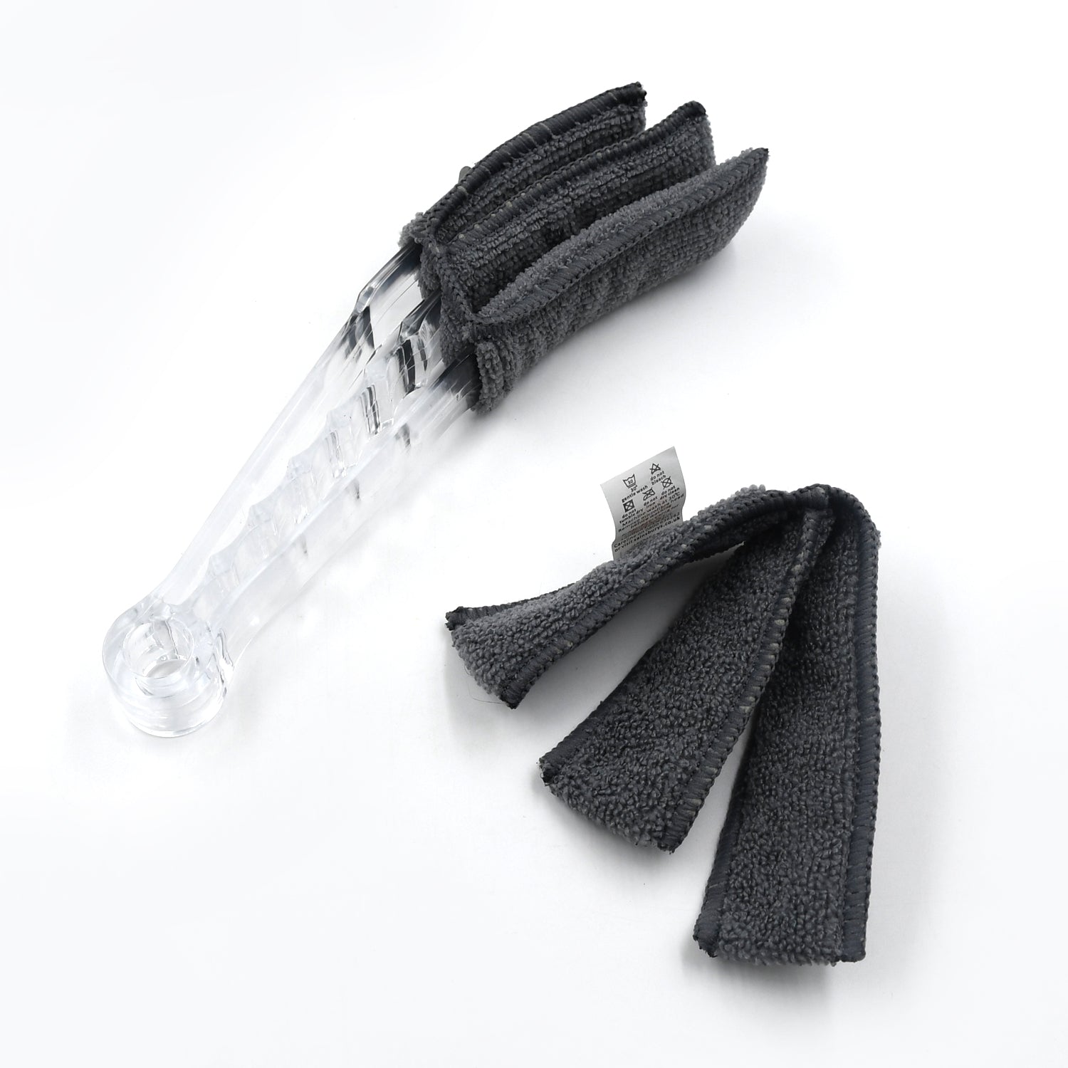 The compact blind cleaner brush being used to clean dust from a car's AC vent.