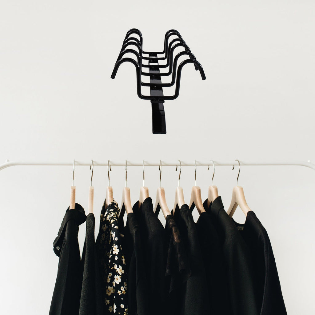 Versatile metal hanger rack holding kitchen utensils and towels.