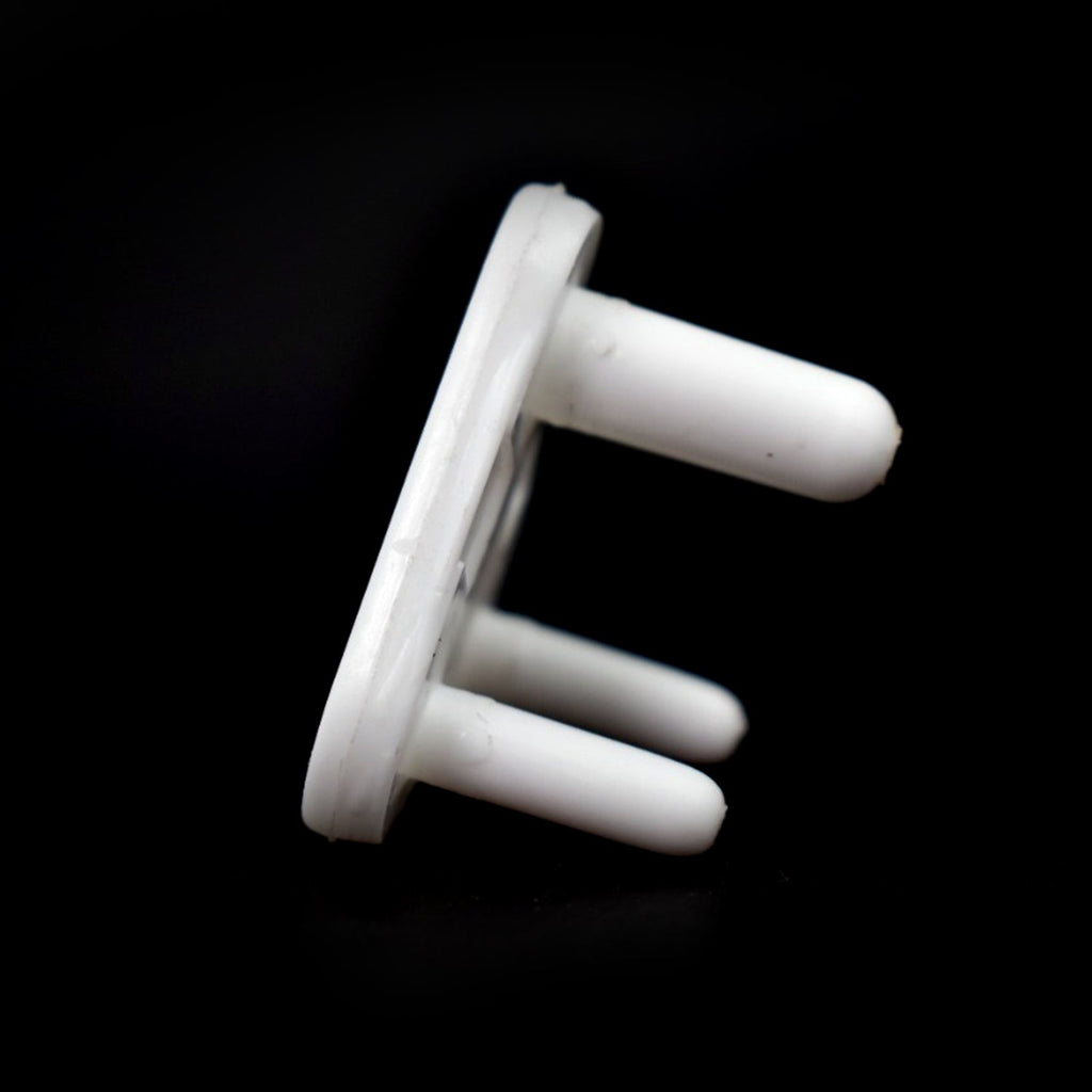 Close-up of a white baby safety socket cover protecting an outlet.
