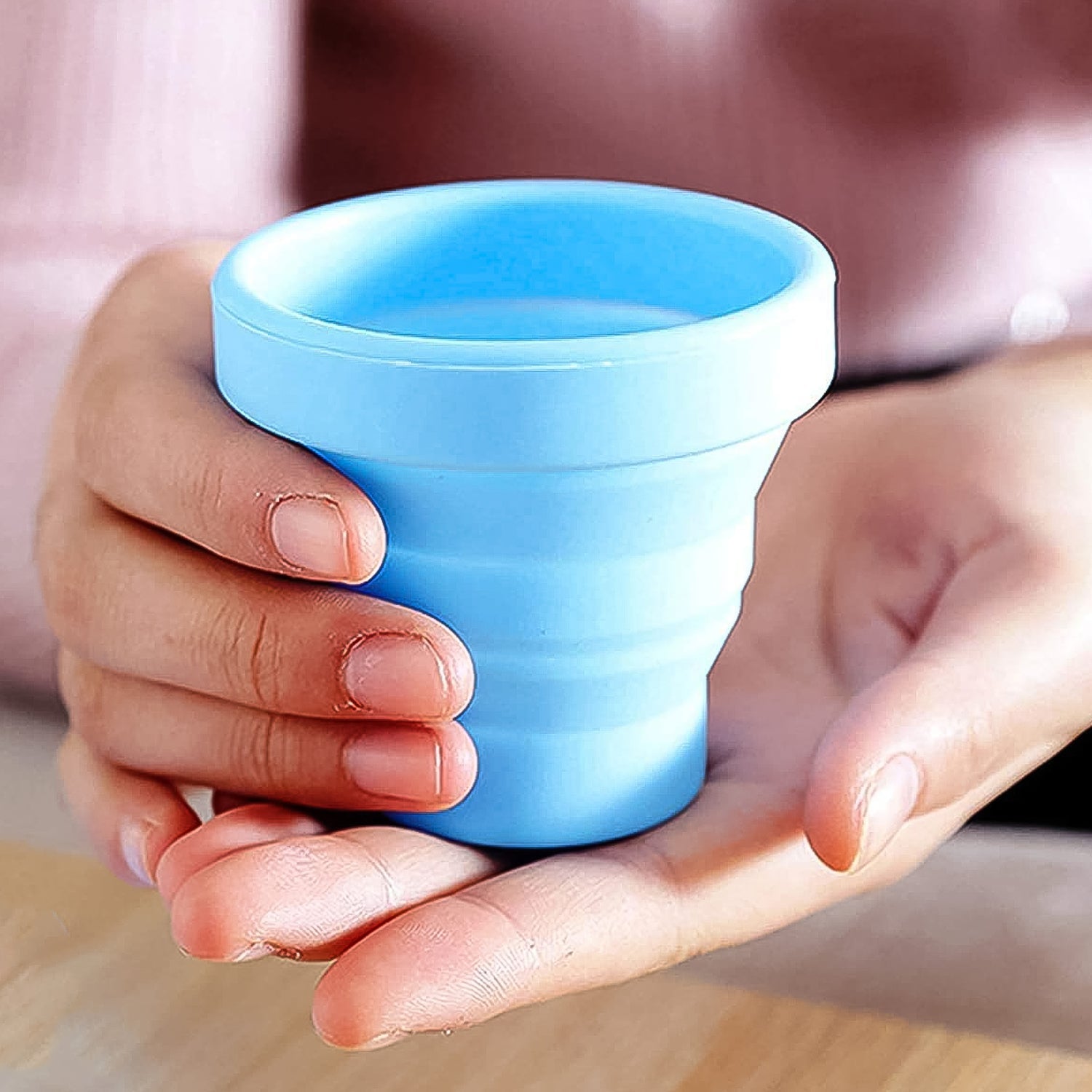 Foldable silicone travel mug in blue, collapsed and expanded, showing its portable design.