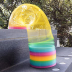 A Rainbow Slinky Toy gracefully moving down stairs, illustrating its classic spring action.