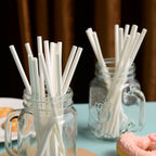 Plain white paper straws held by hands showing 200mm length and 6mm diameter
