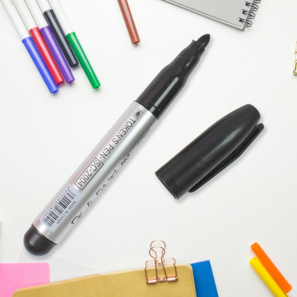 Hand holding a black marker, writing clearly on a notebook, illustrating its use.